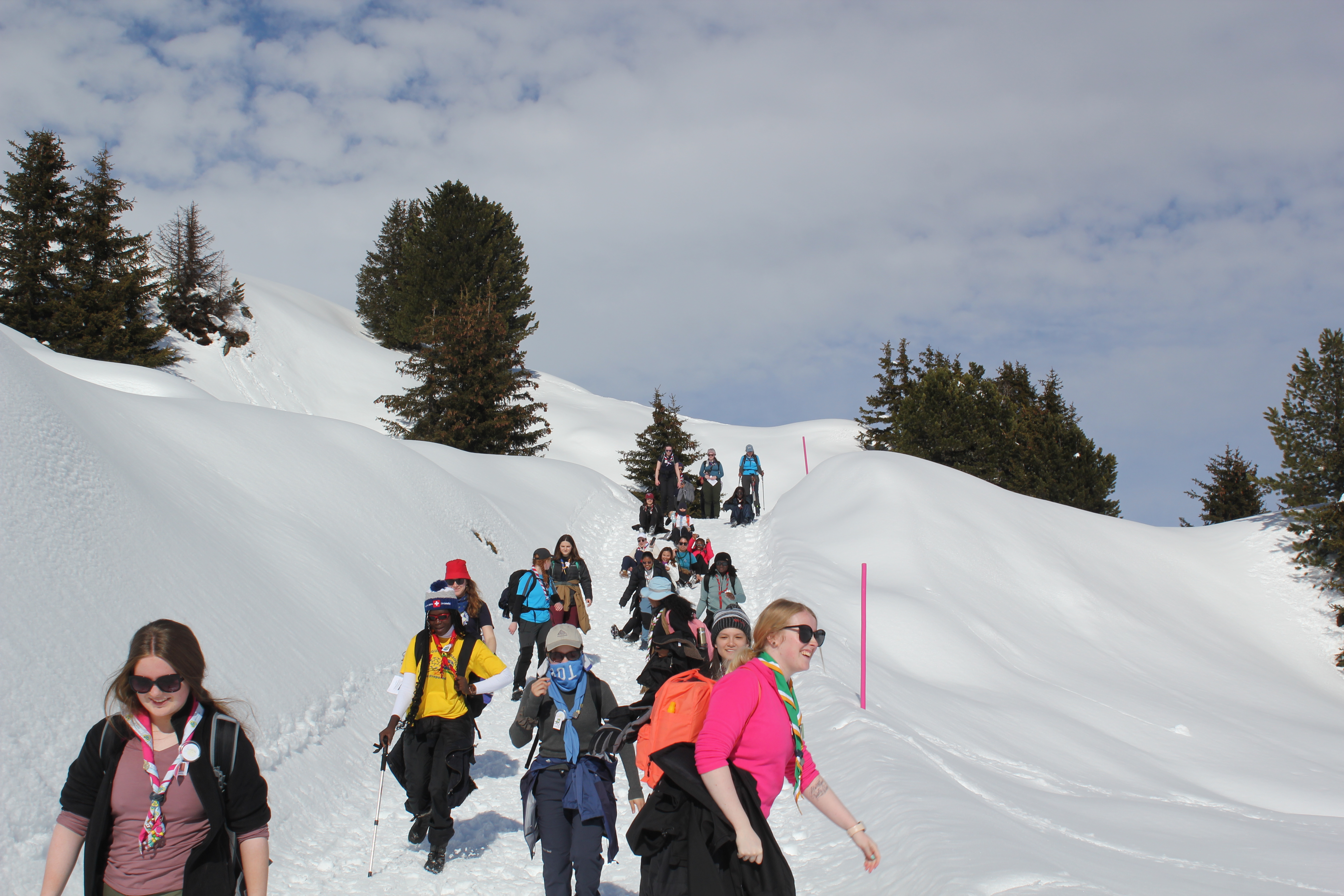 Image of young women in colourful clothes and wearing neckerchief scarves coming down a snowy hill