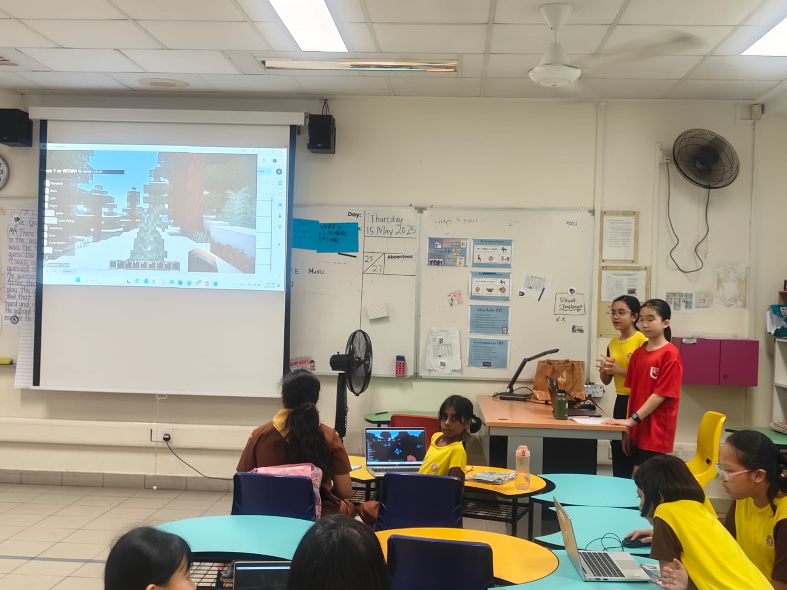 two peer leaders stood at the front of a classroom explaining to their peers who part of the minecraft game works