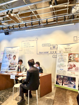 image of a stall at a talk event where the Girl Scouts of Japan are presenting their project to a participant at the event